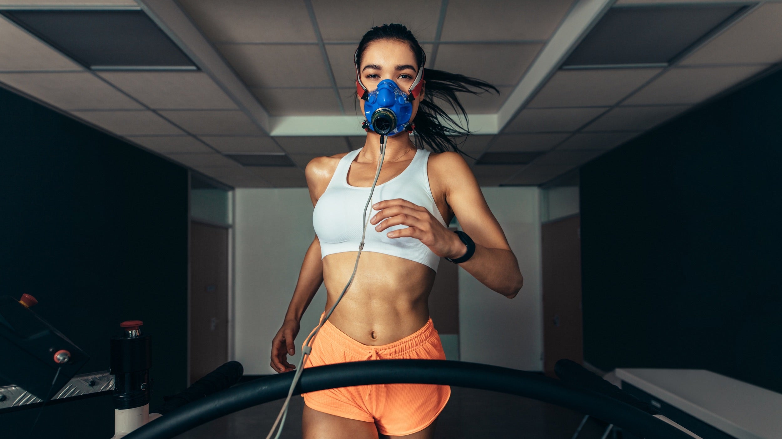 A woman in a mask on a treadmill during Jyzen's body optimization program