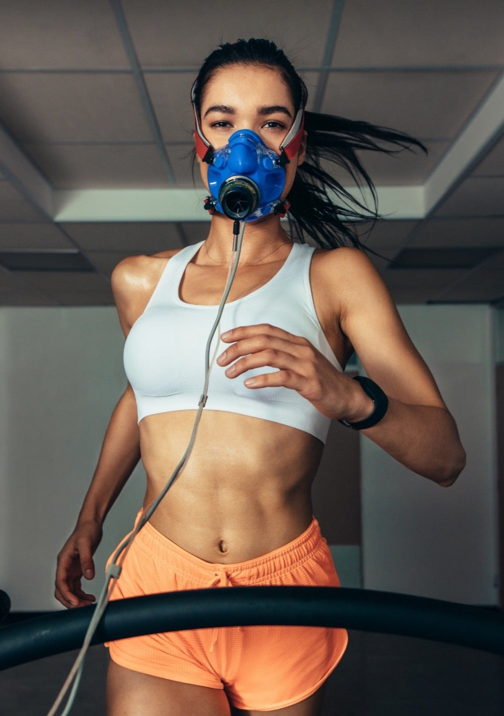 A woman in a mask on a treadmill during Jyzen's body optimization program